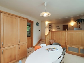 A kitchen with wooden cabinets, a white table, and a clock on the wall.