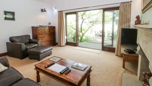 A spacious living room with a fireplace, a large sliding glass door leading to a patio, and a ceiling with a unique arched design. - Frog Meadow Barn (Stoke-on-Trent)