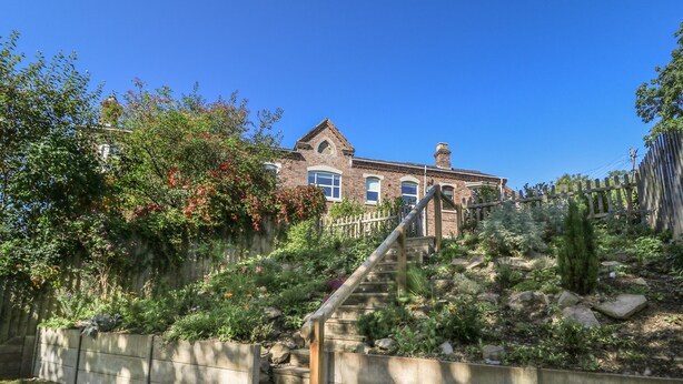 A brick building with a stone staircase leading up to a gated entrance. - Ty'r Orsaf (Builth Wells)