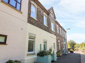 A row of terraced houses with white and brown facades, small windows, and a clear sky.