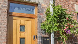 A wooden door with a sign above it, a mailbox, and a brick wall. - Ty'r Orsaf (Builth Wells)