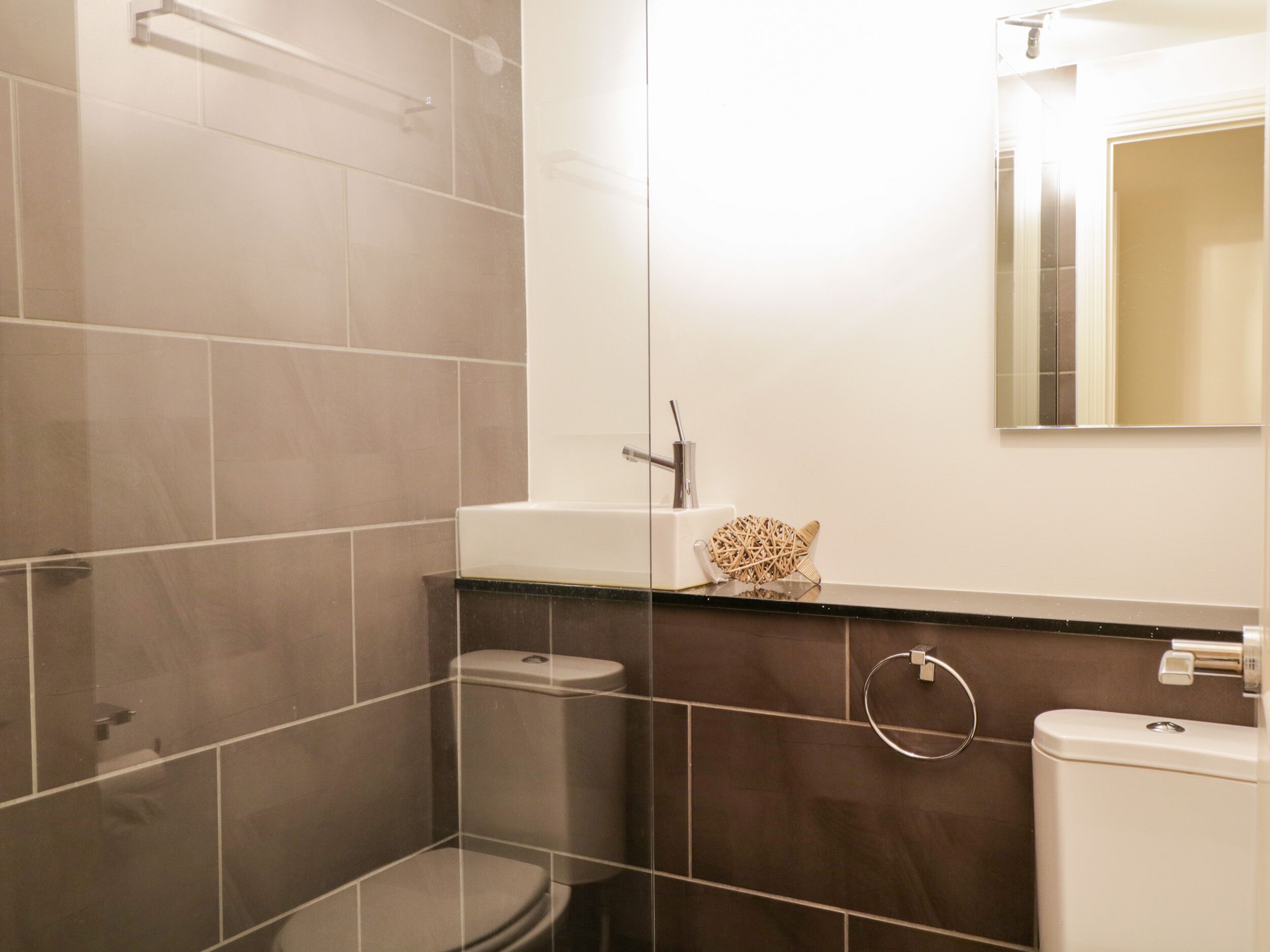 A modern bathroom with a shower, toilet, and sink.