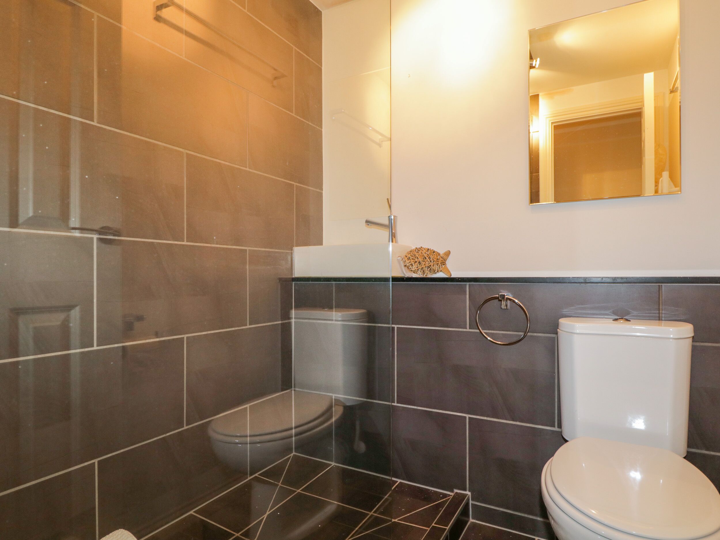 Ein Badezimmer mit zwei Toiletten, einem Waschbecken und einem Spiegel.