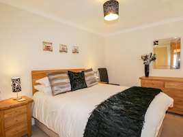 Un dormitorio con cama, mesitas de noche, un espejo y decoración en la pared.