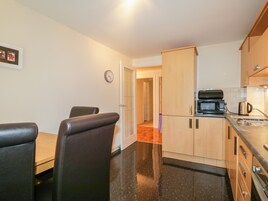 Cocina compacta con comedor, microondas, tetera y un reloj en la pared.