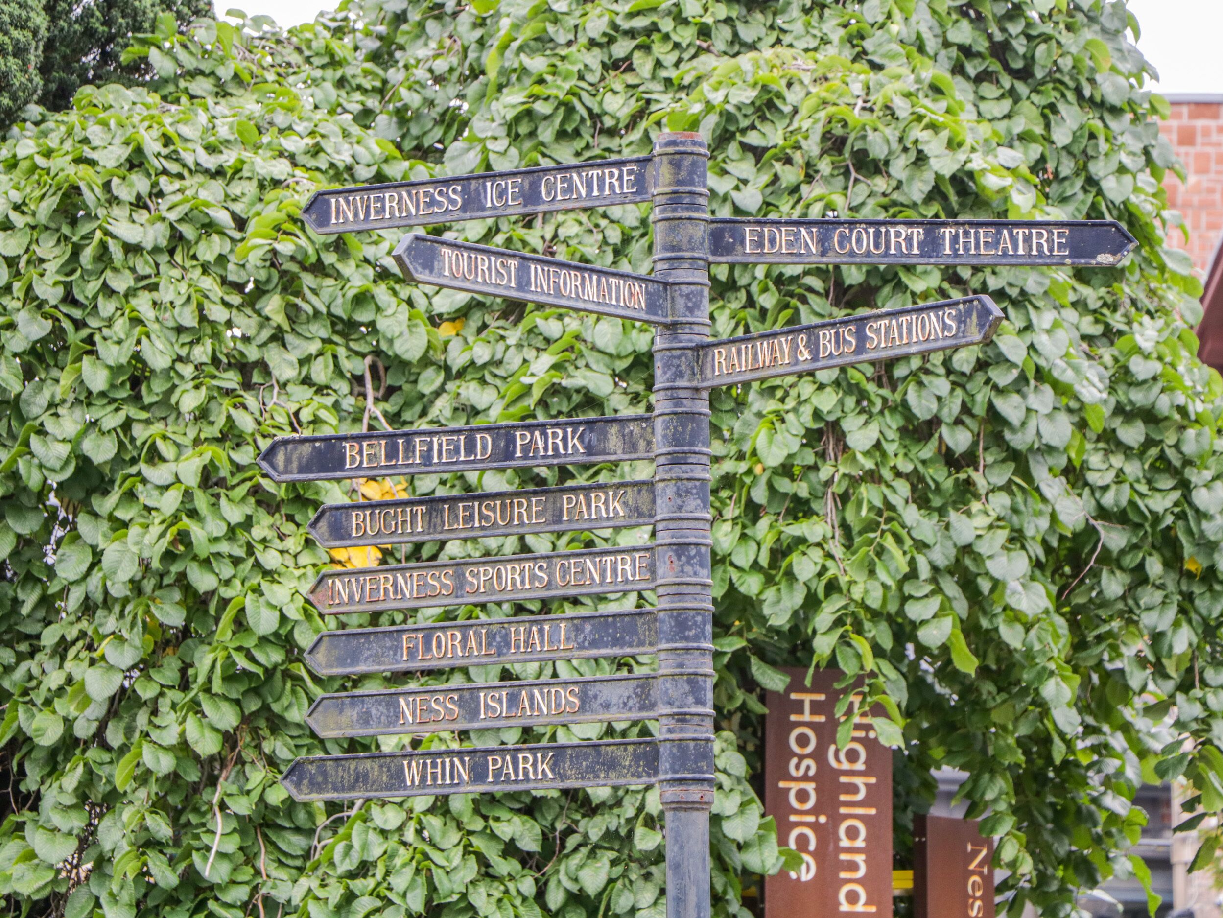 A directional signpost with multiple arrows pointing to various local attractions such as the Eden Court Theatre, Inverness Ice Centre, and Inverness Sports Centre.