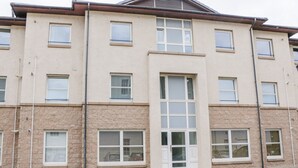 A multi-story building with a symmetrical facade, featuring evenly spaced windows and a central entrance with a glass door. - 7 Riverside Gardens (Inverness)