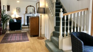 Ein geräumiges Wohnzimmer mit Treppe, Holzboden und einem grünen Teppich.