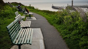A coastal walkway with benches, a lighthouse, and a pier. - Mews Cottage (Whitby)