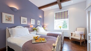 A bedroom with two beds, a wooden floor, a window with a view, and a chair. - Mews Cottage (Whitby)