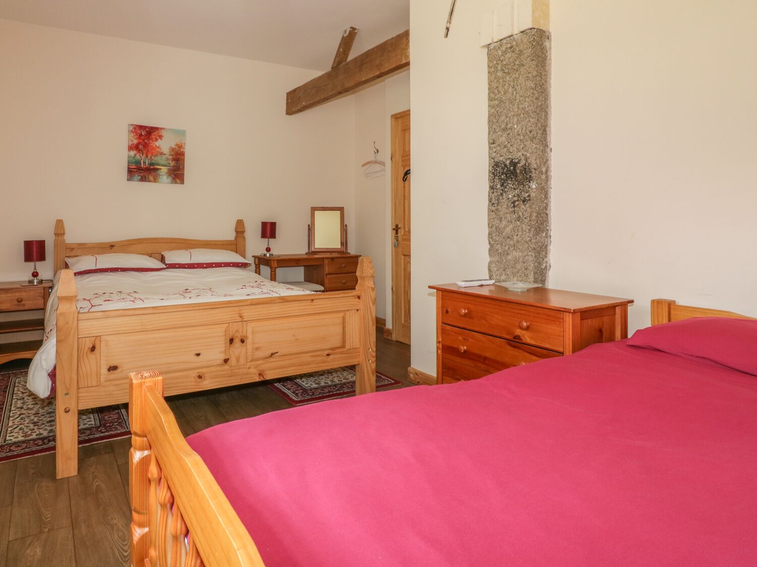 A bedroom with a wooden bed, a nightstand, a dresser, and a painting on the wall.