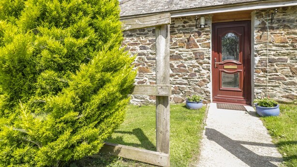 A stone building with a wooden door and a small garden area.