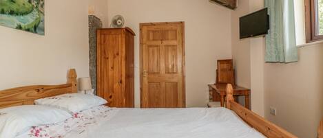 Un dormitorio con una cama grande, un armario de madera, un escritorio y un televisor en la pared.