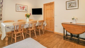 A dining area with a wooden table and chairs, a vase of flowers, and a wooden bench.