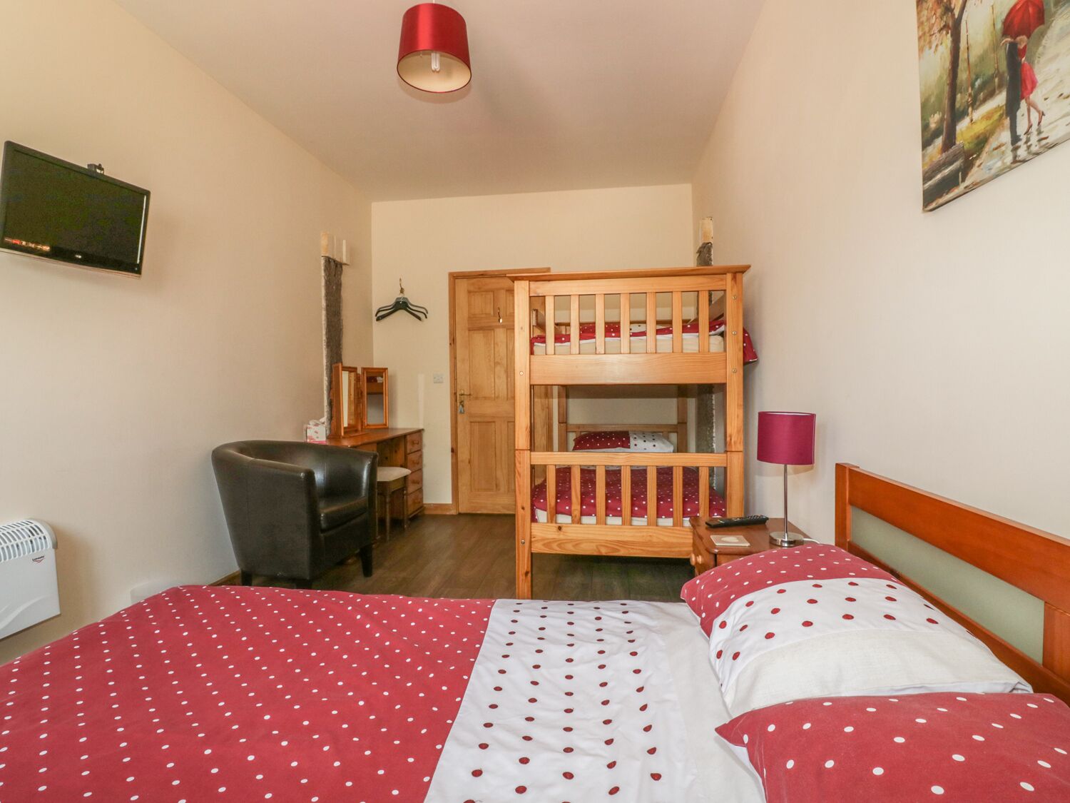 A bedroom with a bunk bed, a desk with a chair, a lamp, and a painting on the wall.
