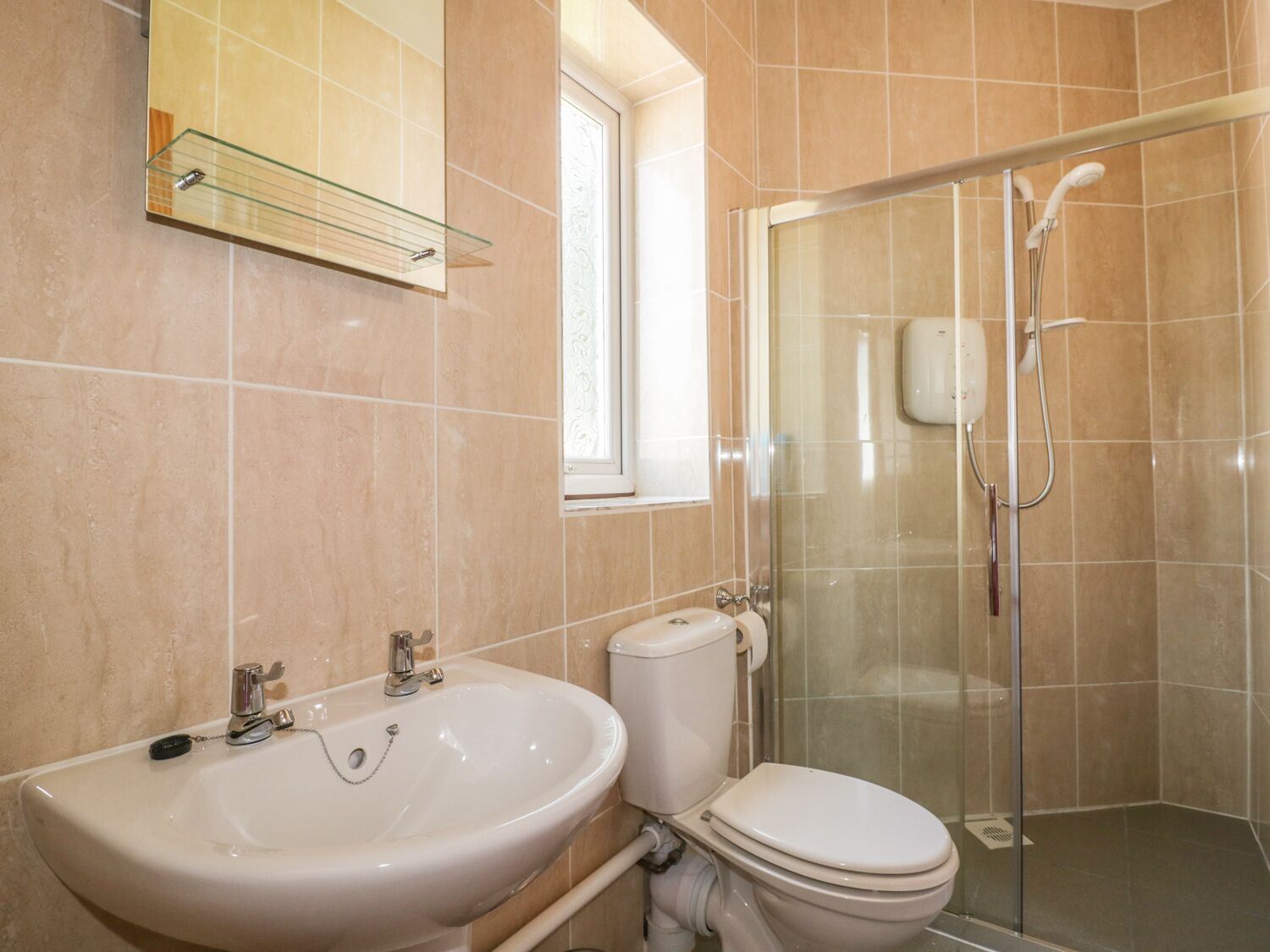 A bathroom with a sink, toilet, and glass shower enclosure.