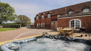 Un jacuzzi dans un jardin, avec une maison en briques et une table à manger.