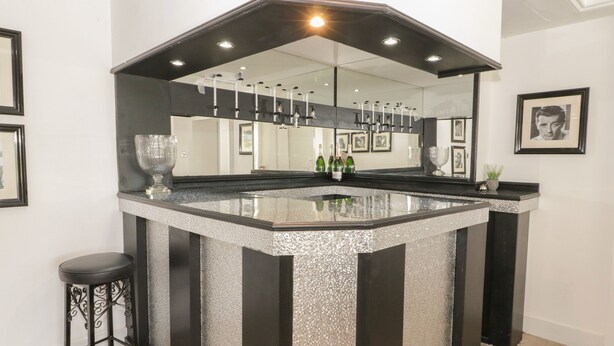 A bar area with a granite countertop, black and white striped columns, and a mirrored backsplash. - Maes Elwy (Saint Asaph)