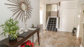 A modern interior with a wooden console table, a mirror, and a potted plant. - Maes Elwy (Saint Asaph)