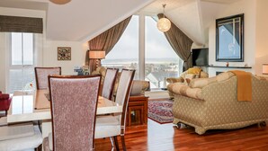 A spacious living room with a dining area, a large window offering a view of the city, and a cozy seating area with a fireplace. - Seaview (Coleraine)