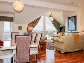 Amplia sala de estar con comedor, un ventanal con vistas a la ciudad y una zona de estar acogedora con chimenea.