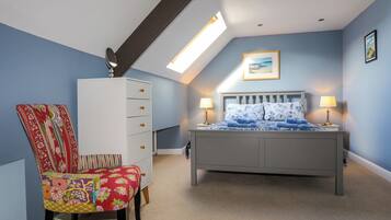 Een slaapkamer met een bed, een dressoir, een stoel en een dakraam.