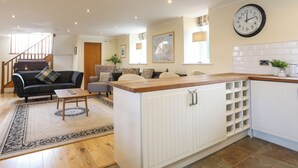 A modern kitchen with white cabinetry, a wooden countertop, and a built-in wine rack. - Capel Hermon (Holyhead)