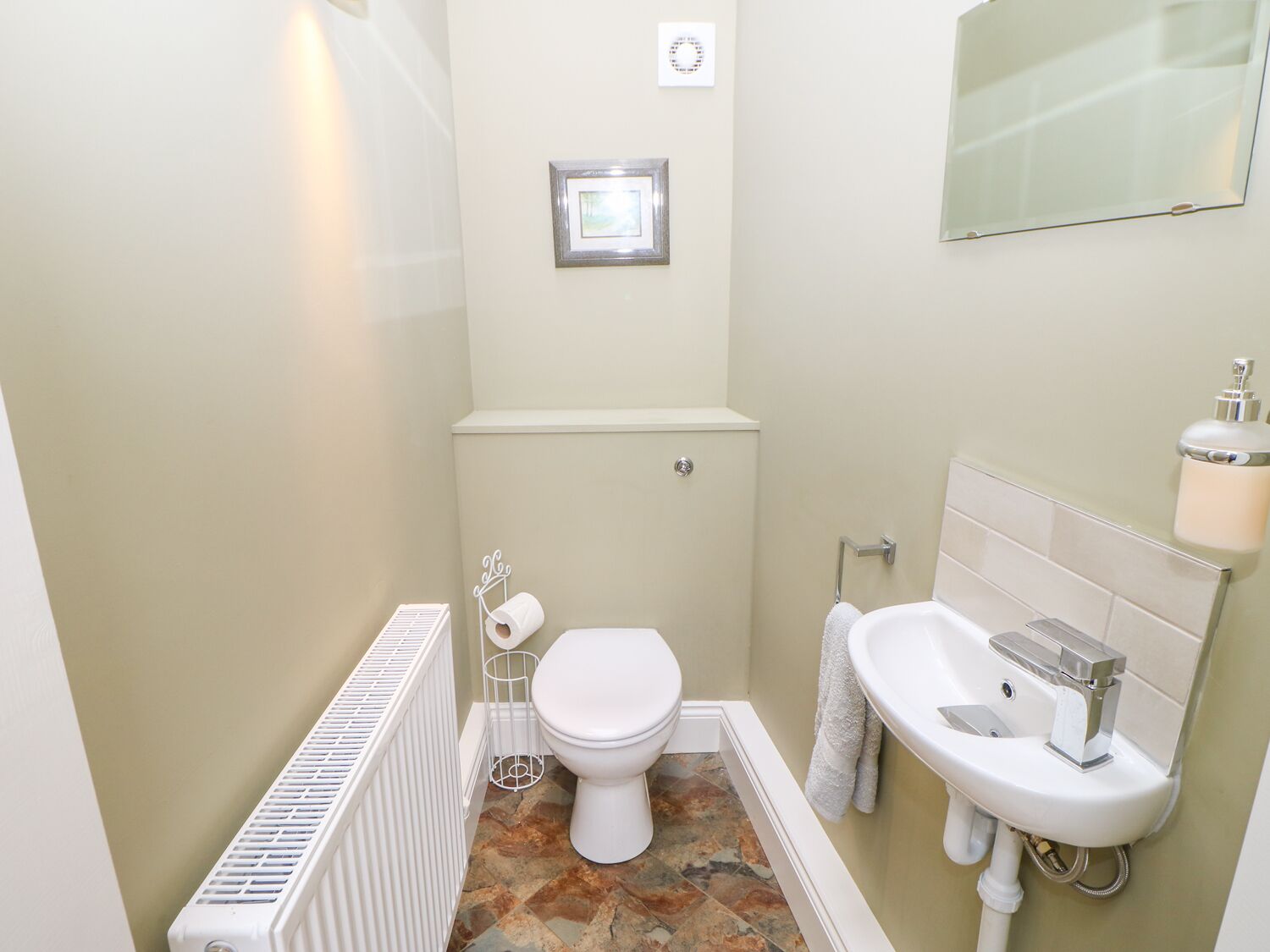 Een kleine badkamer met toilet, wastafel en radiator.