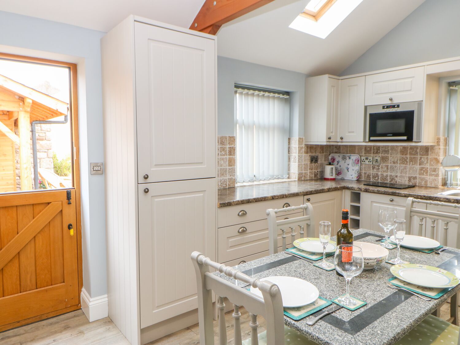 A kitchen with white cabinets, a granite countertop, and a dining table set for four.