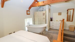 Ein Schlafzimmer mit einem großen Bett, einer Holztreppe, einem Badezimmer mit Badewanne und einer kleinen Kommode.