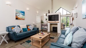 A modern living room with a blue sofa, a coffee table, and a fireplace. - Betony (Bamburgh)