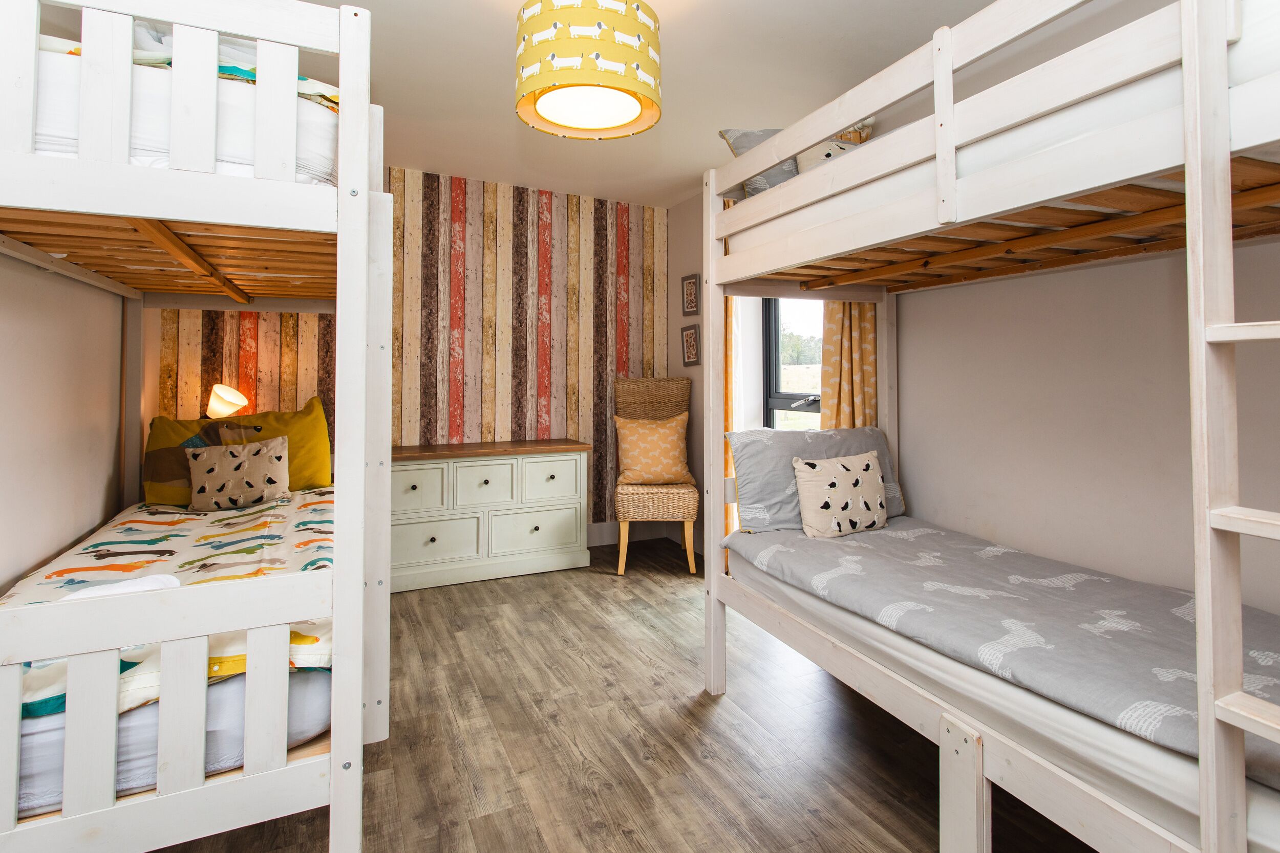 A room with bunk beds, a desk, a chair, and a lamp.