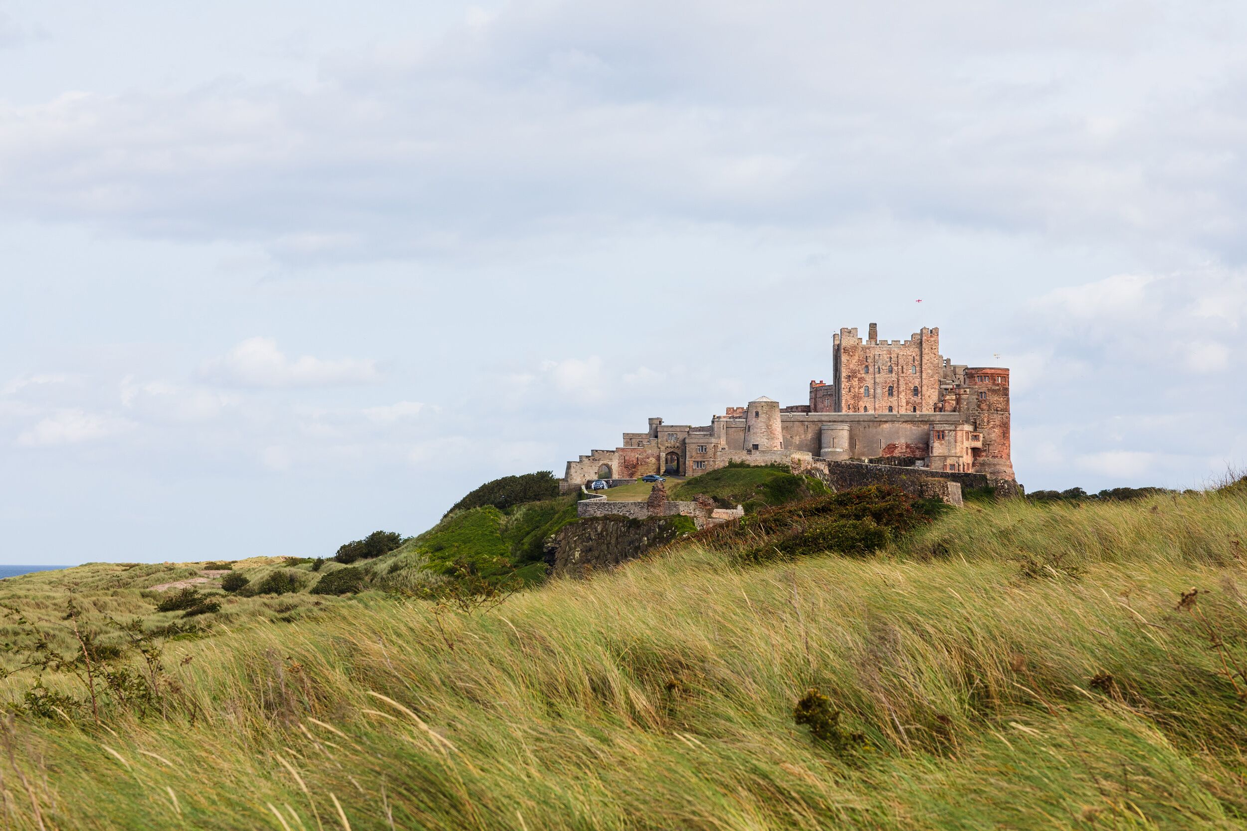 A historic castle on a grassy hill with a clear sky.
