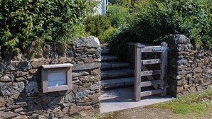 A stone wall with a wooden gate and a sign that reads "WILLOW COTTAGE." - Willow Cottage (Dartmouth)