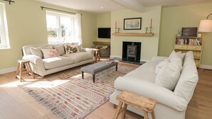 A spacious living room with a fireplace, a sofa set, a coffee table, and a bookshelf. - Willow Cottage (Dartmouth)