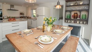 A modern kitchen with a central island, white cabinetry, and a variety of kitchen appliances. - Willow Cottage (Dartmouth)