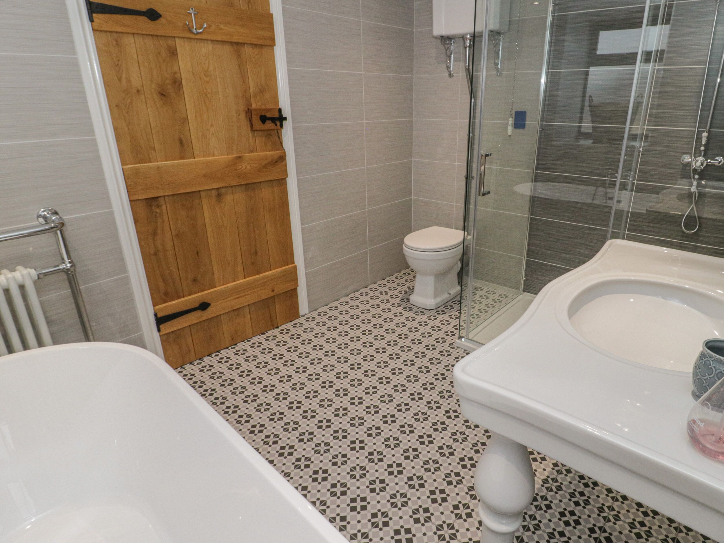 A bathroom with a wooden door, a toilet, a glass shower enclosure, and a white bathtub.
