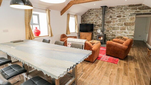 A cozy living area with a stone wall, a fireplace, a dining table with chairs, and a television.