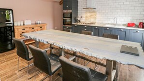 A modern kitchen with a marble countertop, wooden chairs, and a large dining table.