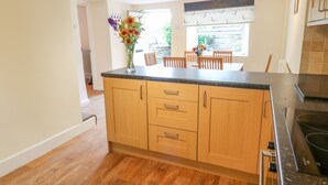 A modern kitchen with wooden cabinets, a black countertop, and a built-in stove. - Stone Farm Cottage (Sheffield)