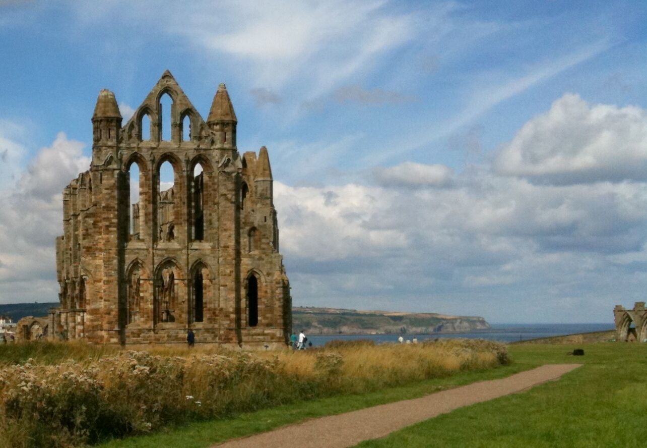 A historic stone building with multiple arches and a pathway leading to it.