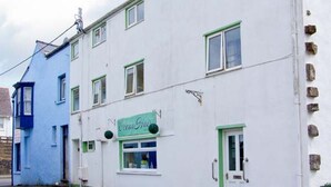 En vit byggnad med gröna detaljer och en skylt med texten ”Coco’s Café”.
