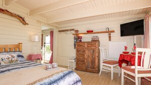 A cozy bedroom with a bed, a dresser, a chair, and a television. - Songbird Hideaway (Pwllheli)