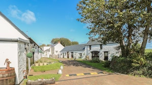 A rural street with stone buildings, a paved path, and greenery. - Bluebell Cottage (Milford Haven)