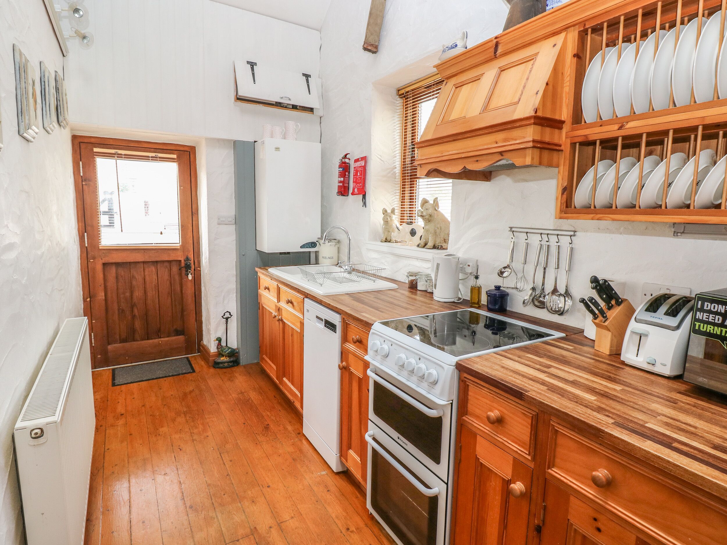 Une cuisine compacte avec des meubles en bois, un lave-vaisselle encastré, une cuisinière et une petite fenêtre.