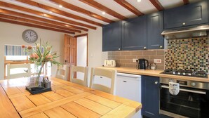 Une cuisine avec des poutres en bois, un poêle, un lave-vaisselle et un revêtement mural en carreaux.