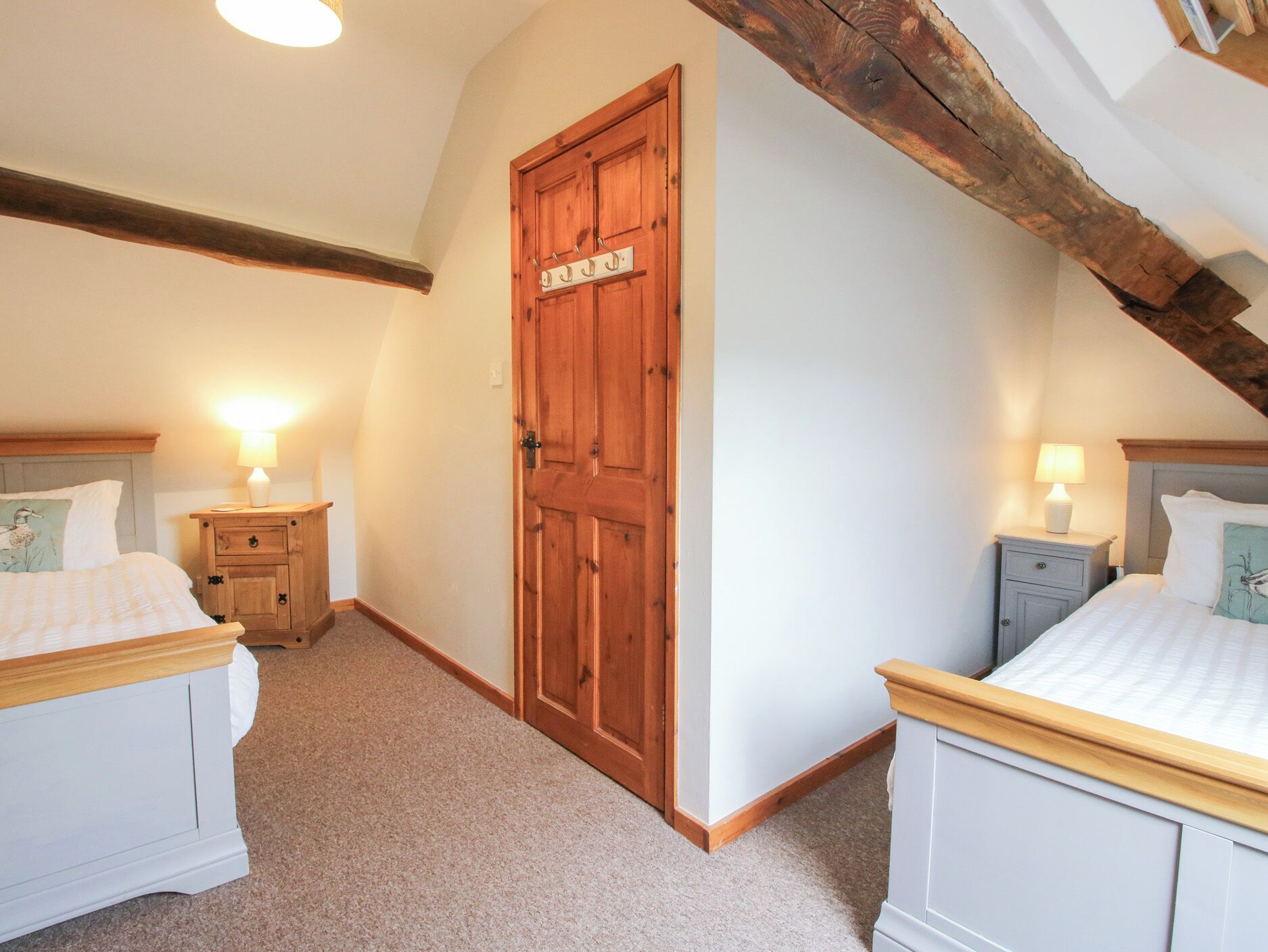 Ein Schlafzimmer mit zwei Betten, einer Holztür und einer geneigten Decke.