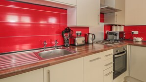 Una cocina moderna con salpicadero rojo, electrodomésticos de acero inoxidable y encimeras de madera.