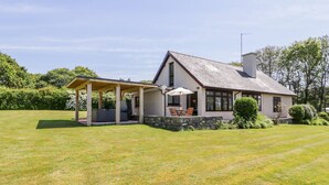 Une maison dotée d’un patio couvert, de fondations en pierre et d’une pelouse.