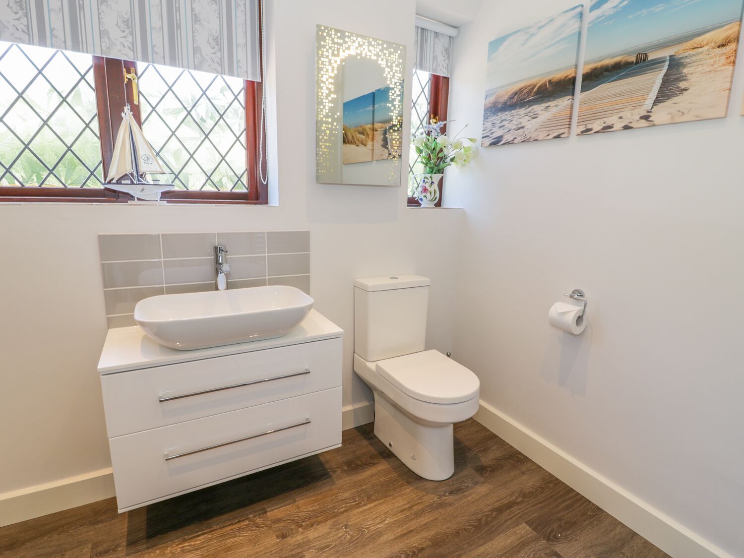 A bathroom with a white sink, a toilet, and a window with curtains.